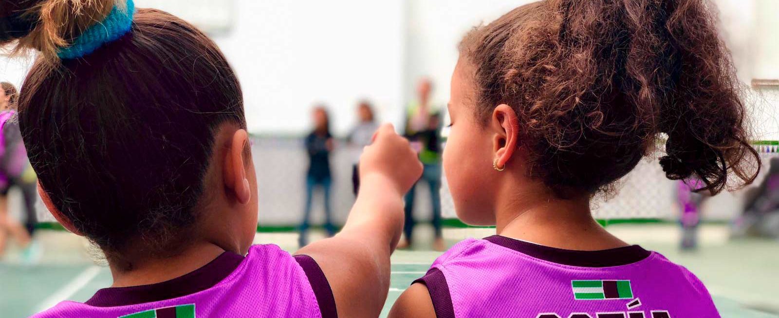 Niñas con camisetas magenta representando al basket femenino